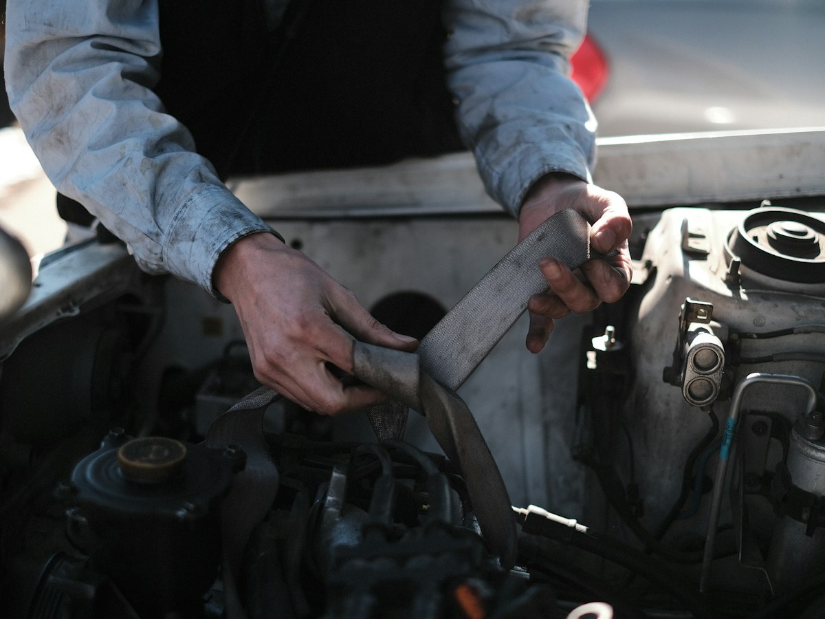 Technician inspecting belts and hoses in an engine bay